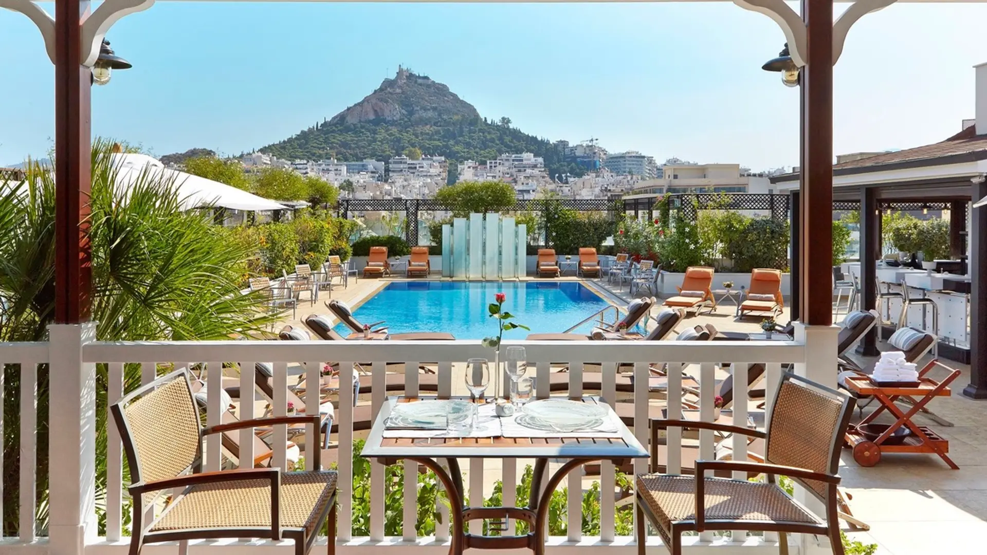 Lunch and pool area, with view to nature, white and wood classical pool design and sunbeds at Hotel Grande Bretagne