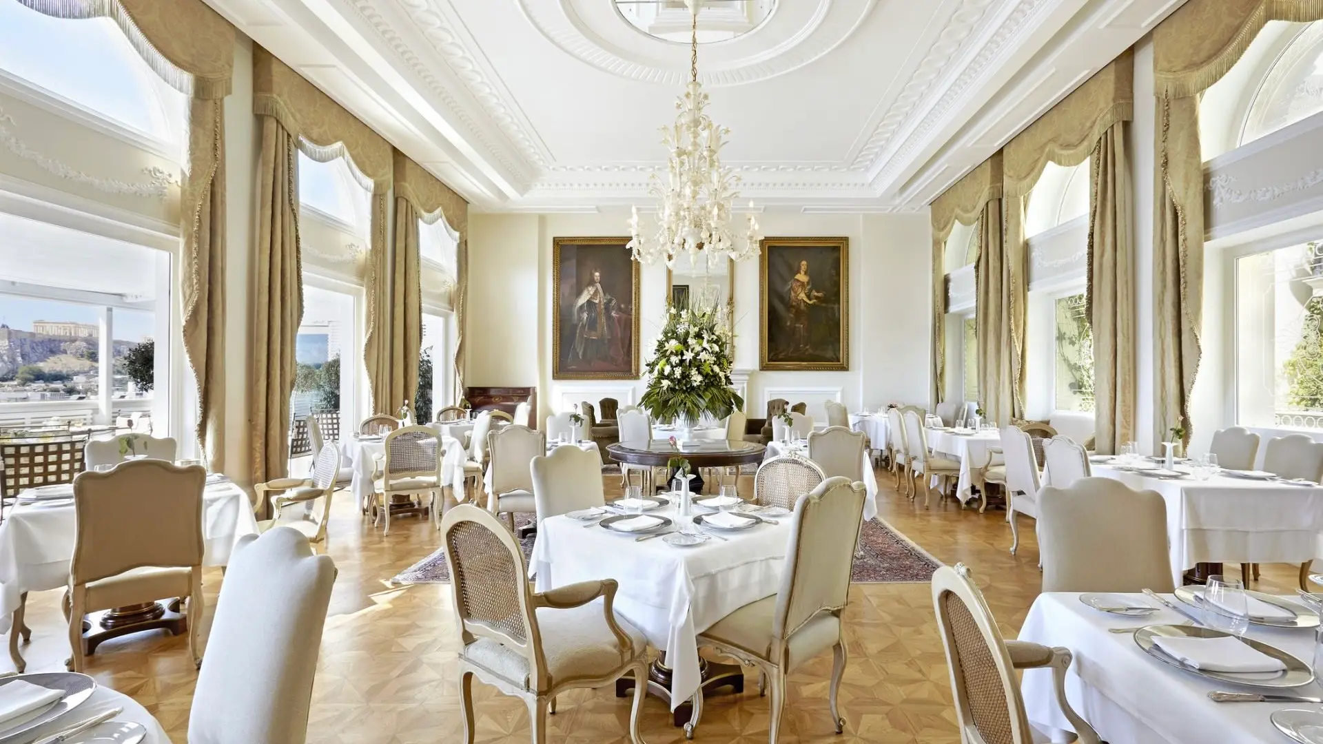 Dining area at King George, white tables with silver plates and plain white leather chairs with also two paintings and wooden floor. 