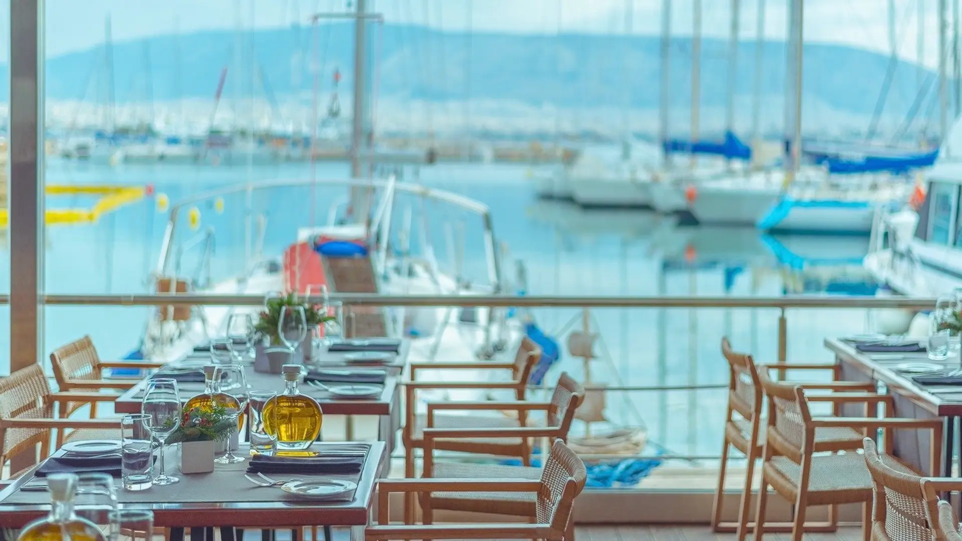 Varoulko Seaside resturant. A indoor resturant by the sea with tree chairs and large glass windows.