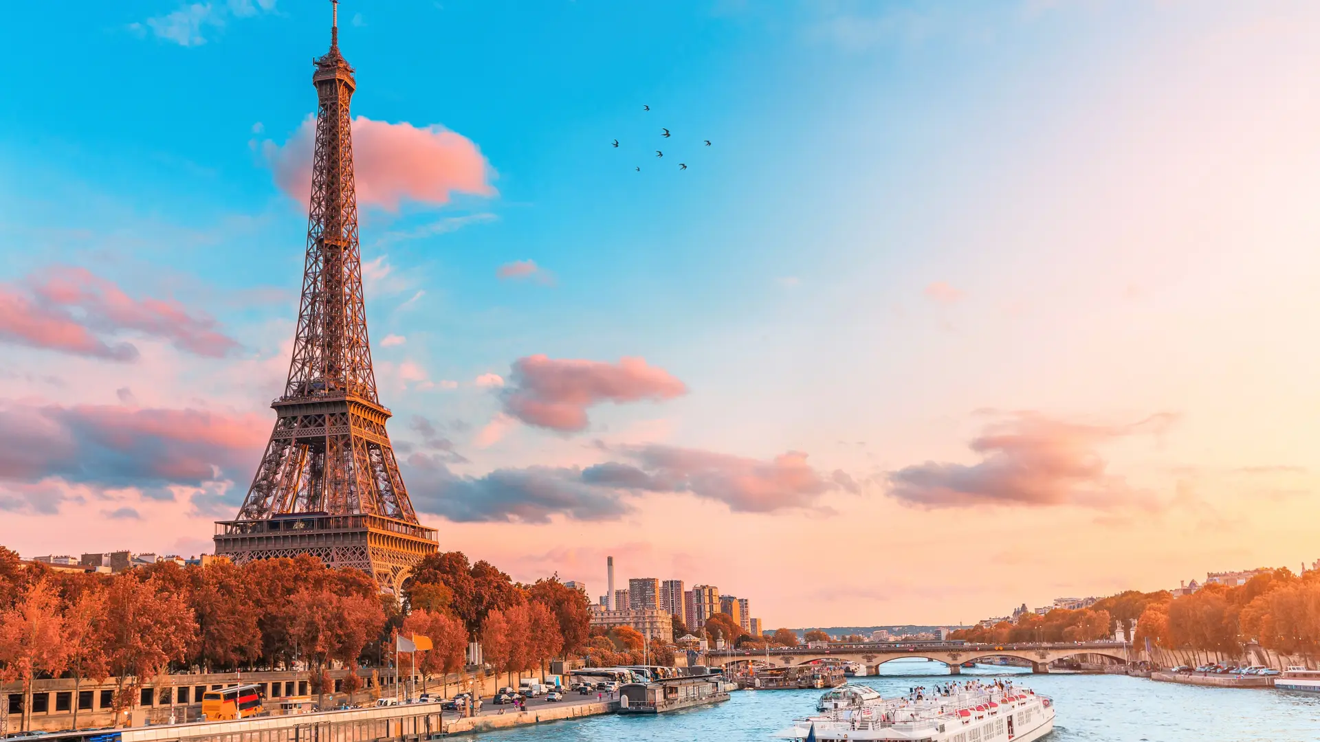 View of the Eiffel tower, large tourist boat, and orange fall trees.