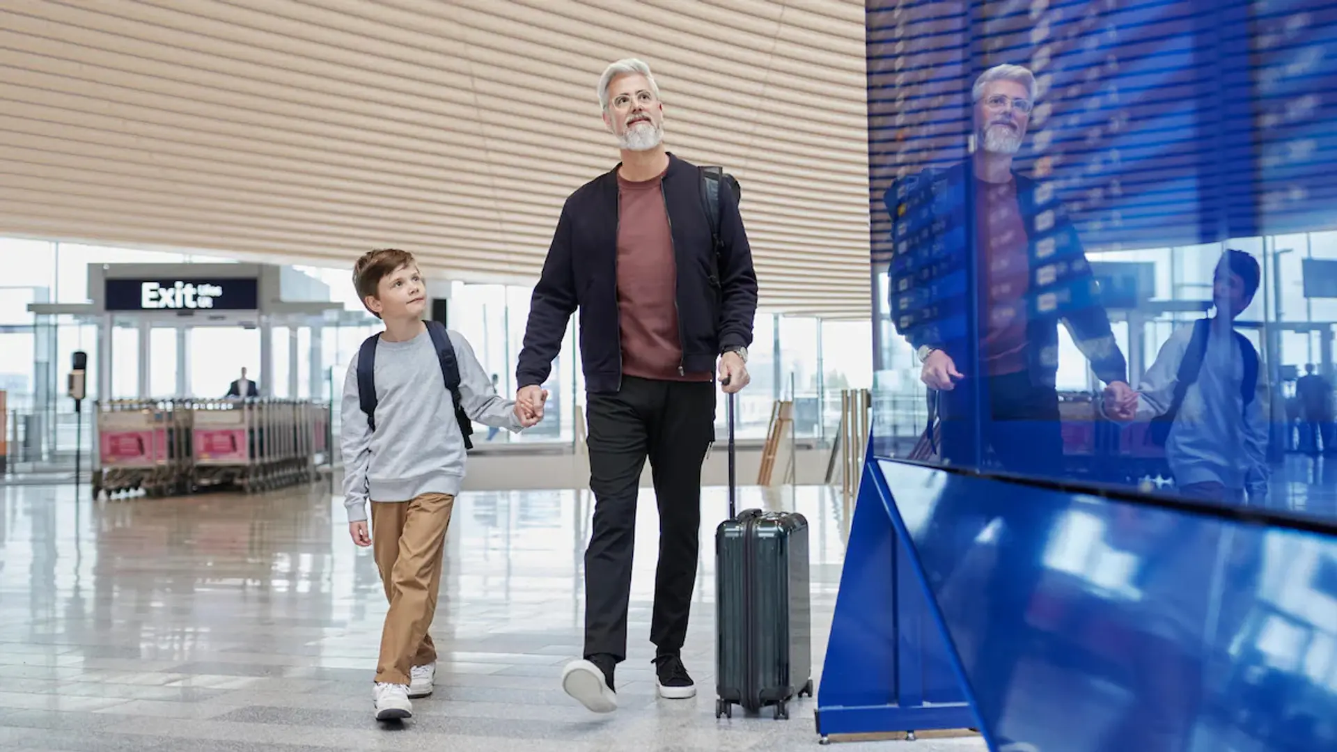 a father holding hands with his son at an airport