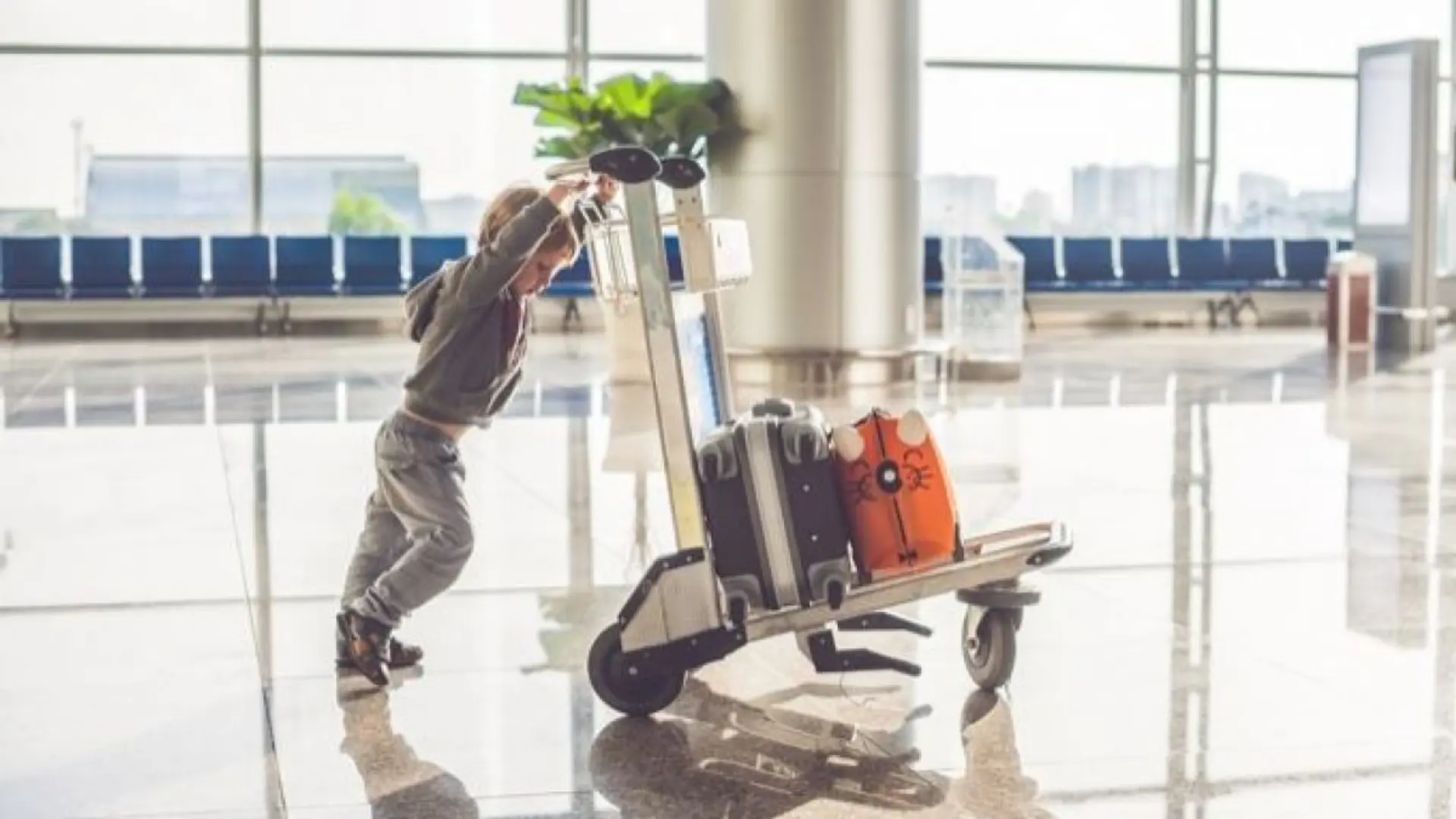 a young boy with a airport trolley and bags