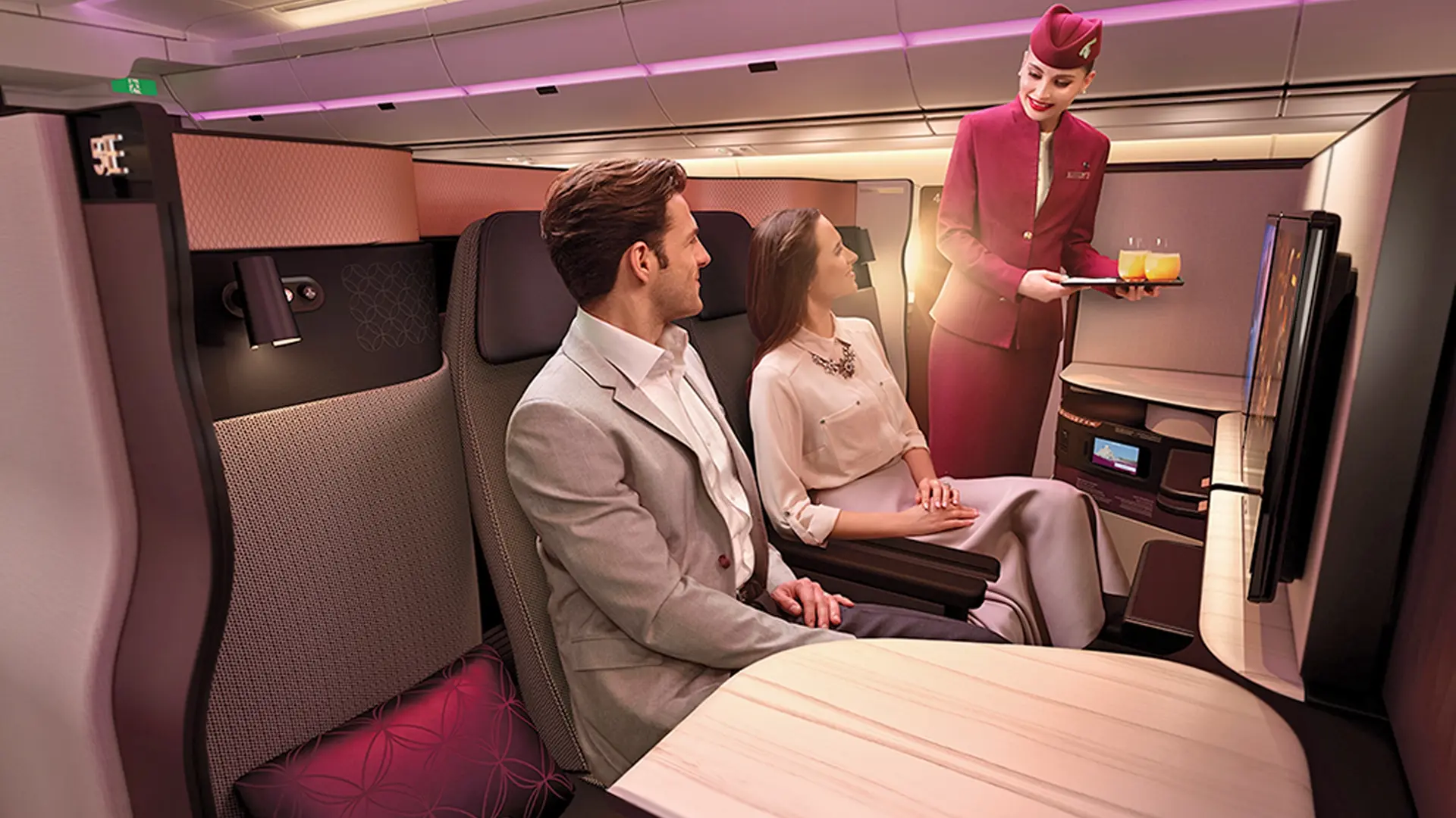 Couple sitting on a business class flight being served orange juice.