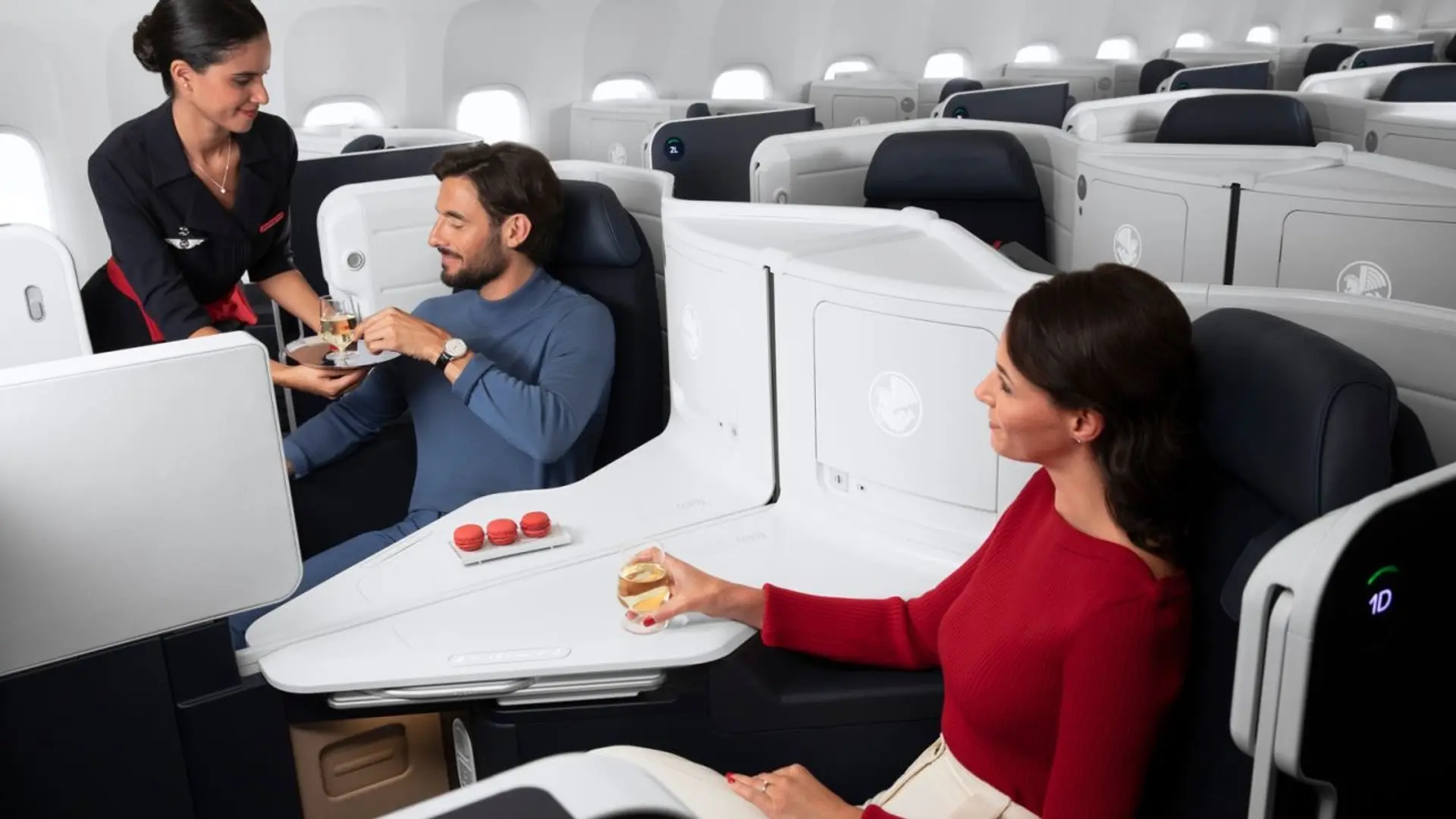 Couple being served champagne bya flight attendant at a businessclass flight.