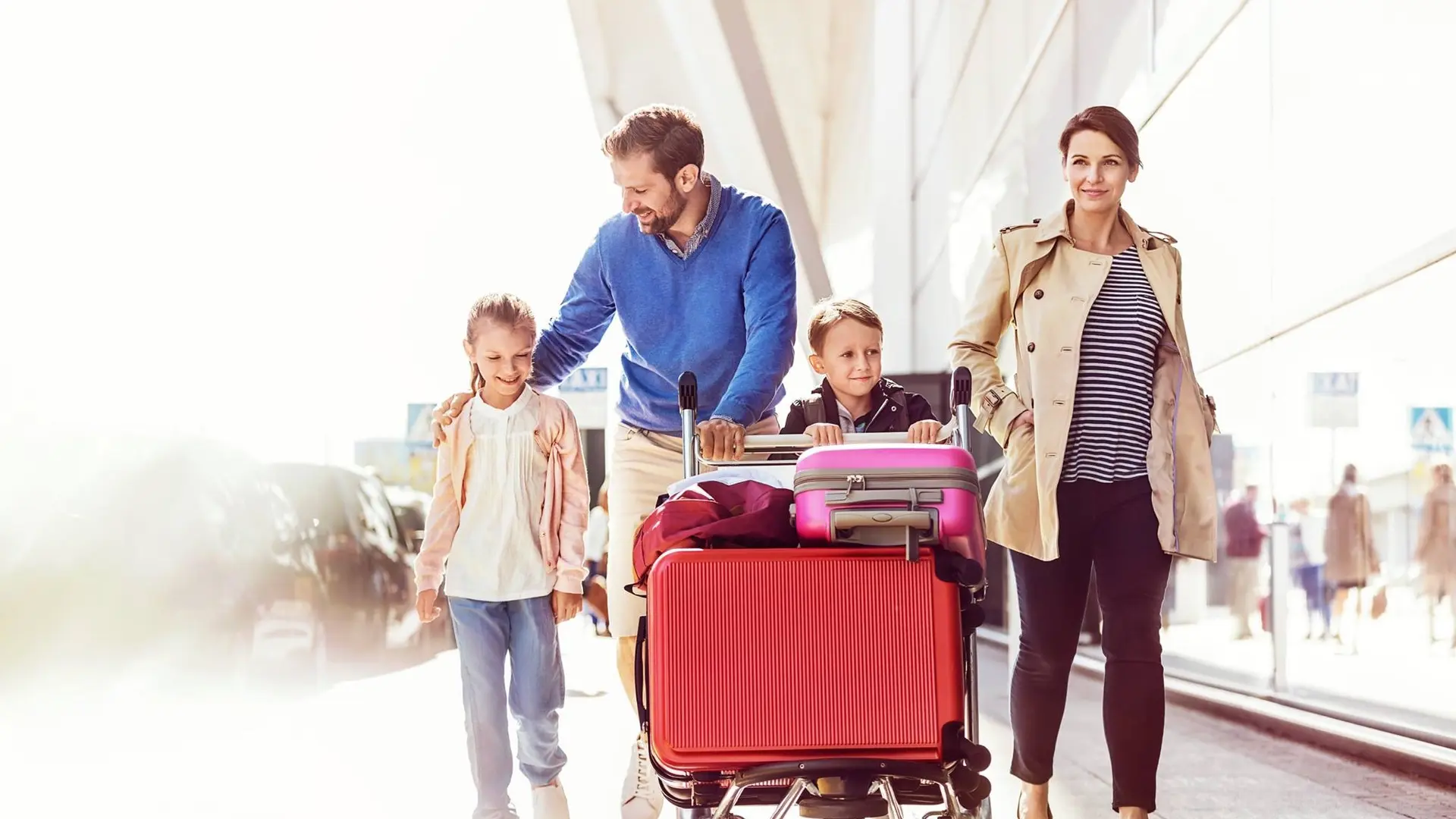 Family of four including one boy, a girl, a man and a woman carrying there suitcases ready for a flight.